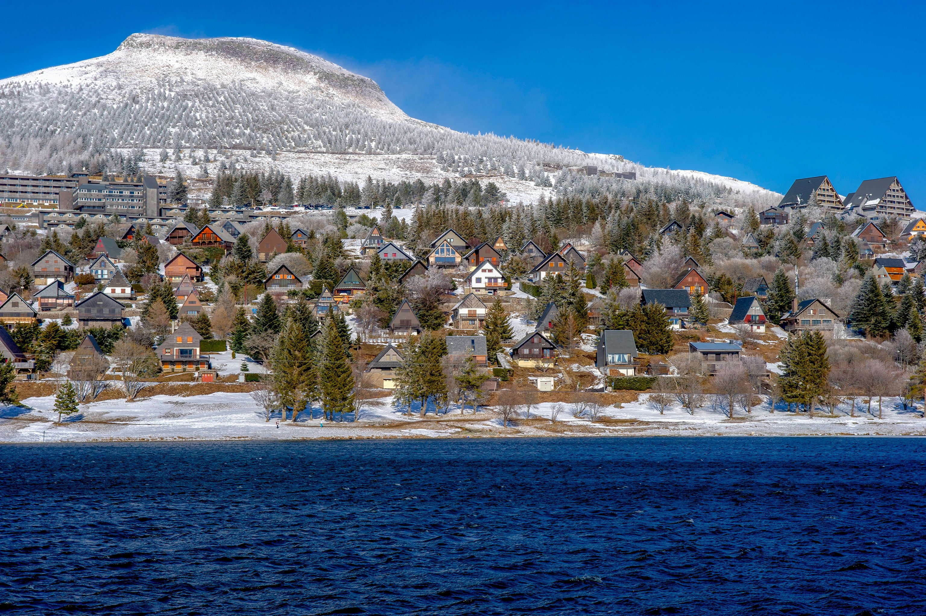 Une ville côtière avec des maisons, une montagne et une étendue d’eau.