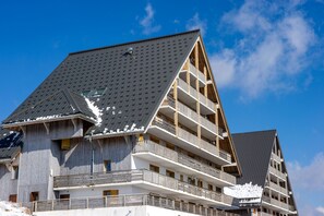 A multi-story hotel with a sloped roof, balconies, and a clear sky.