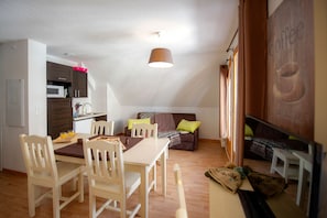 A compact living space with a dining area, kitchenette, and a cozy seating area with a couch and pillows.