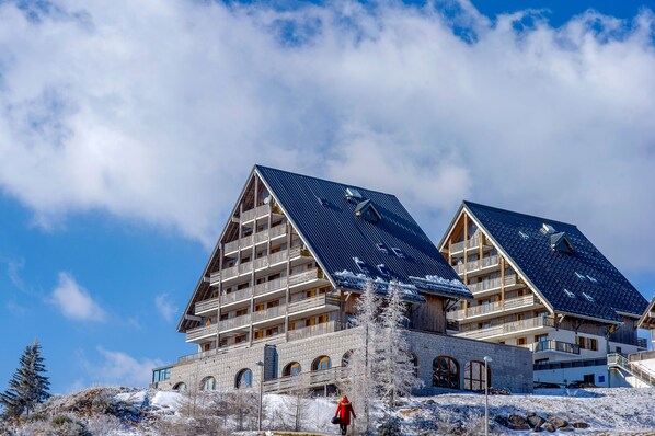 A hotel with a modern architectural design, featuring a prominent sloped roof and multiple balconies.