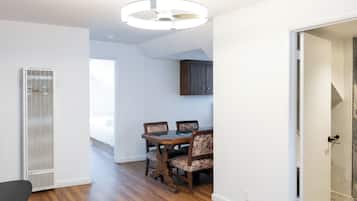 A room with a dining table and chairs, a ceiling light fixture, and a vent.