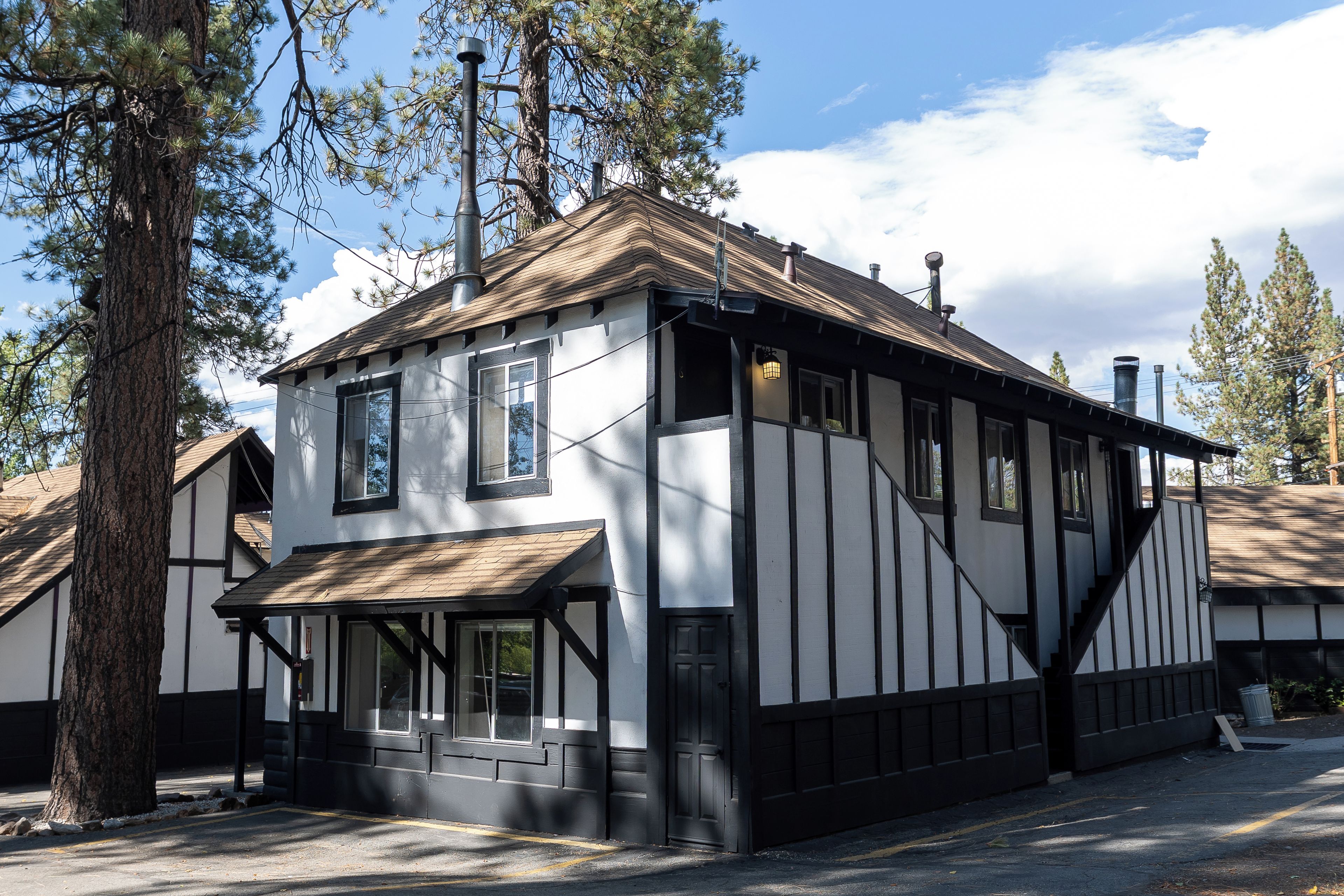 A traditional building with a gabled roof, large windows, and a prominent chimney.