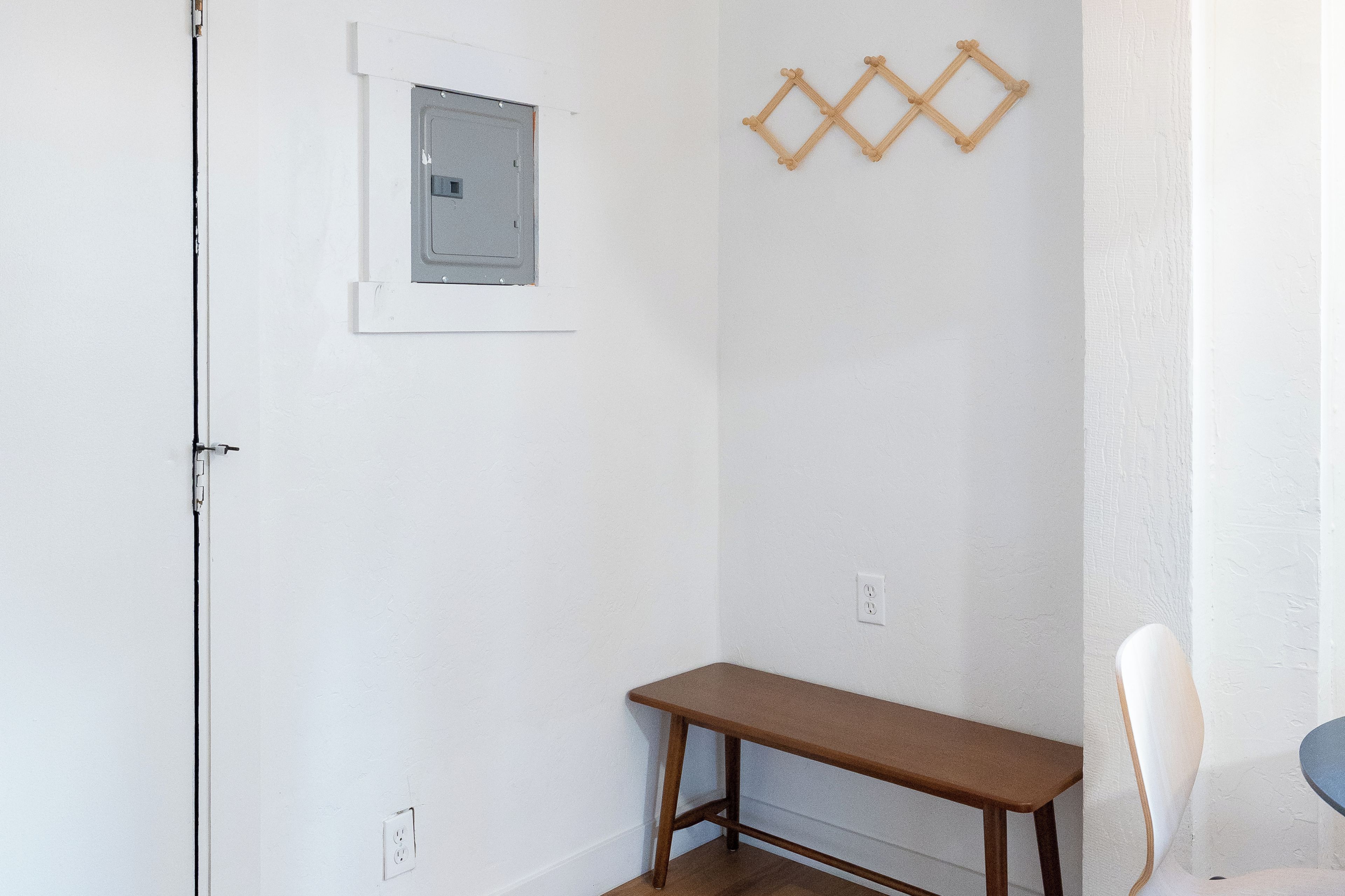 Une pièce avec un banc en bois, une petite fenêtre et un luminaire fixé au mur.