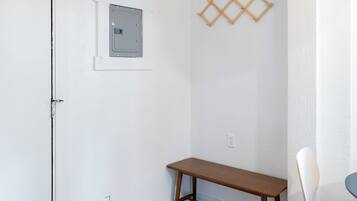 Une pièce avec un banc en bois, une petite fenêtre et un luminaire fixé au mur.