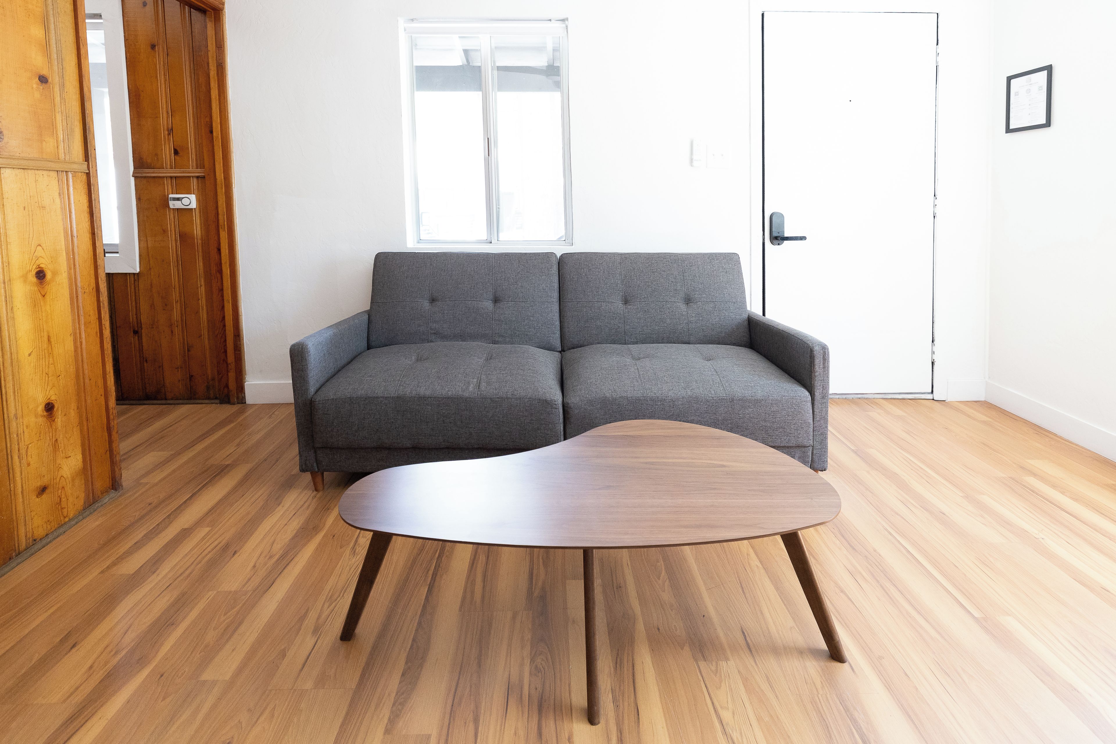 Ein Zimmer mit einem grauen Sofa, einem Holztisch und einem Holzschrank.