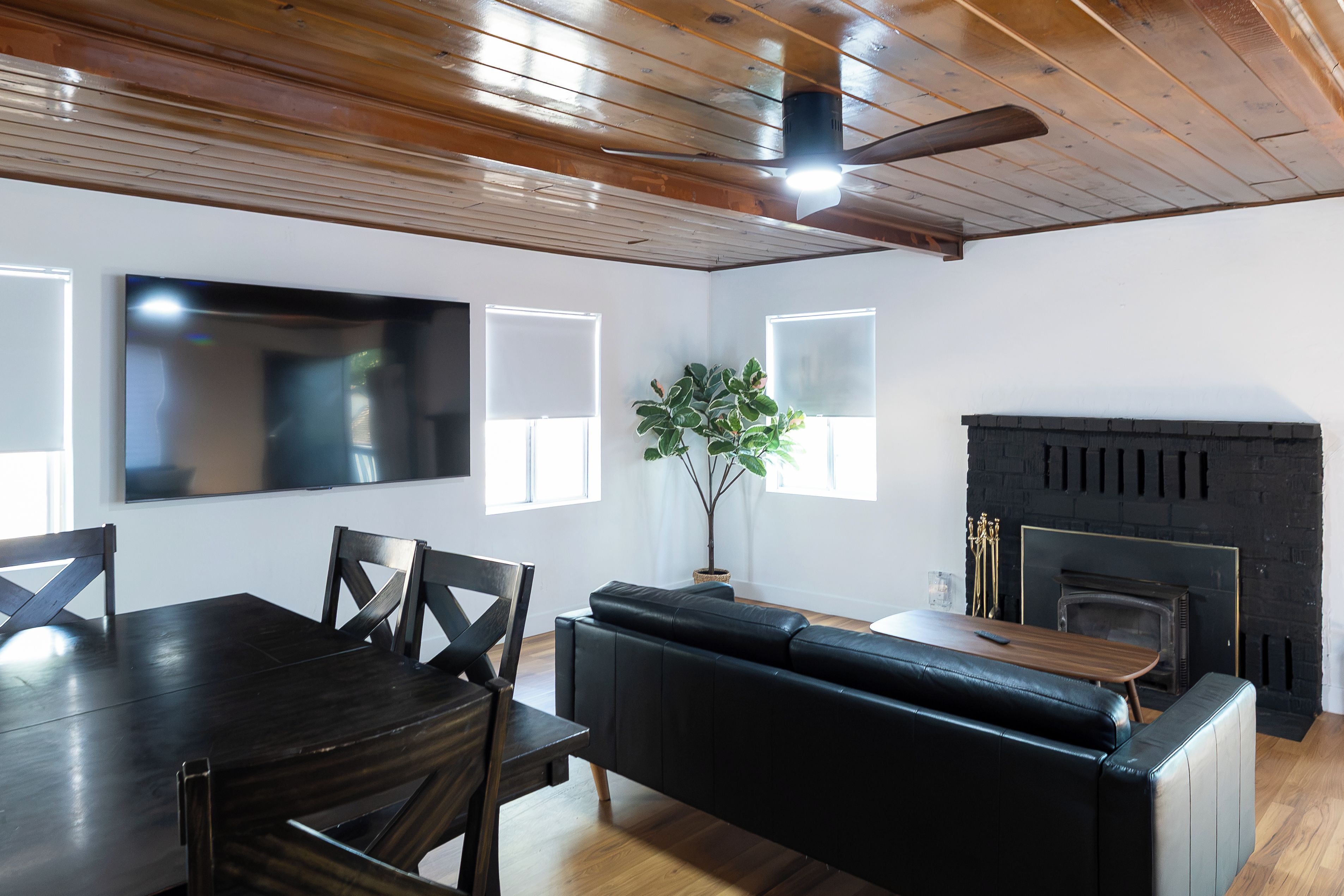 A modern living room with a dining area, a fireplace, and a ceiling fan.
