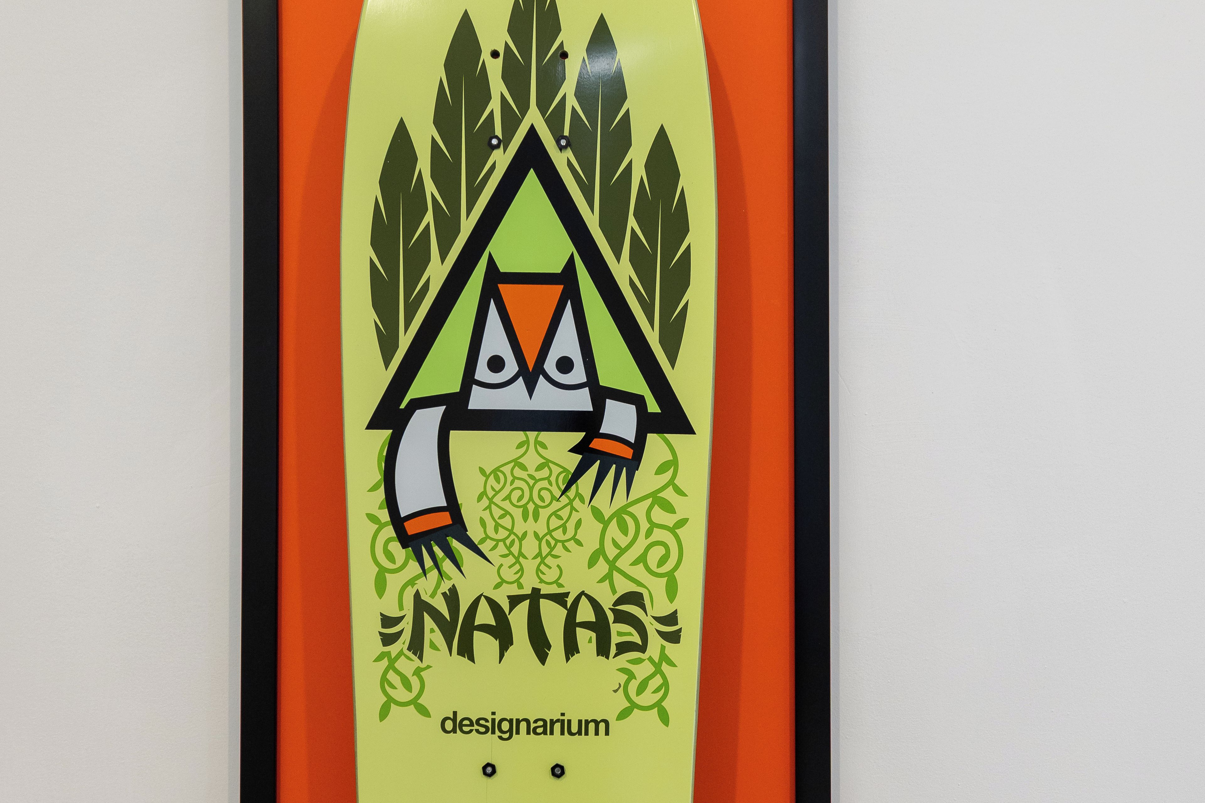 A skateboard with a graphic of a stylized owl and the word 'NATAS' on it.