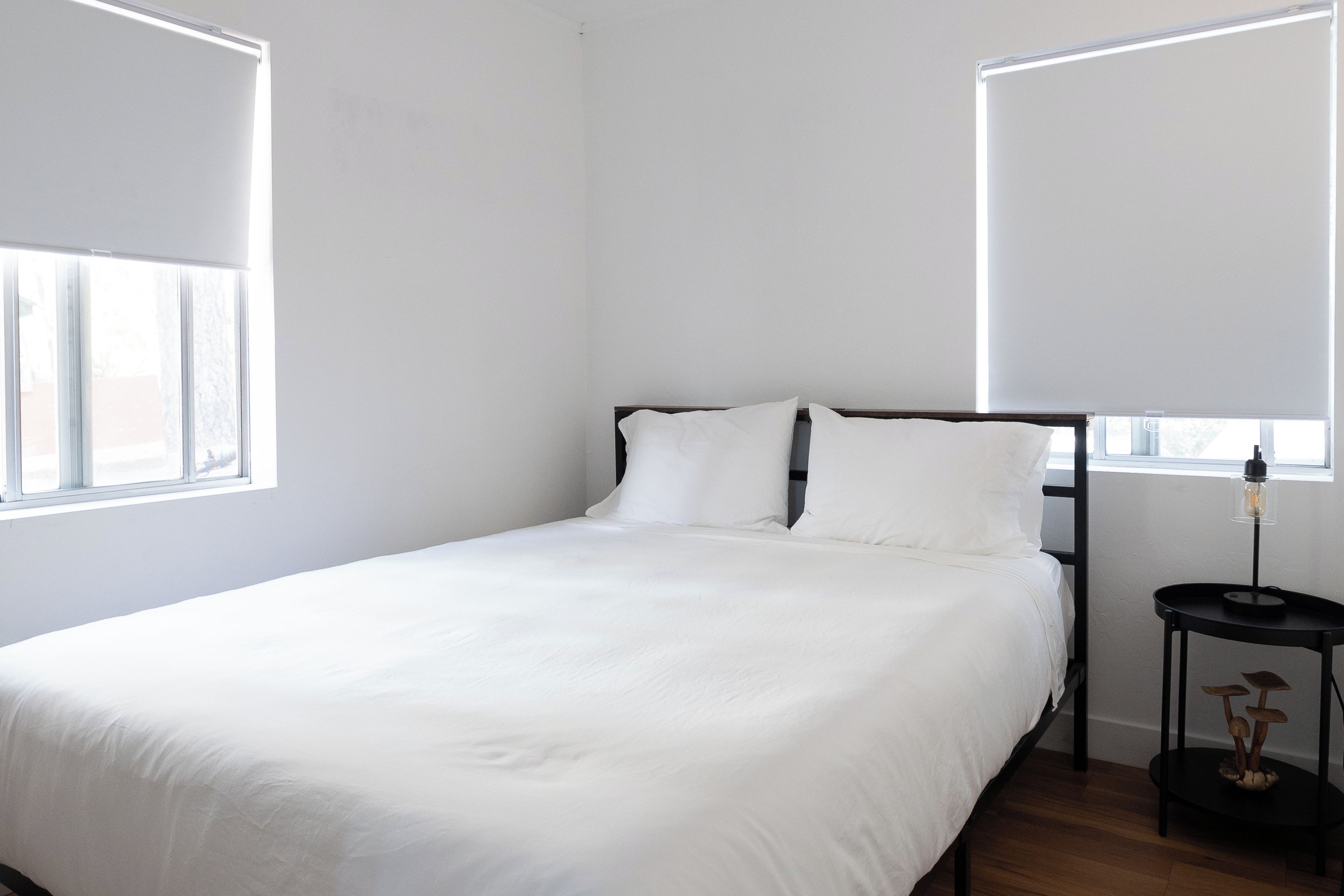 A minimalist bedroom with a single bed, a nightstand, and a wall-mounted lamp.