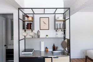 Una kitchenette compacta con estufa integrada, pileta y estanterías para almacenamiento.