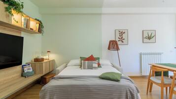 Un dormitorio moderno con cama, mesita de noche, lámpara y televisor.
