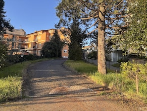 Um caminho de paralelepípedos leva a um edifício residencial de fachada em pedra e várias janelas.