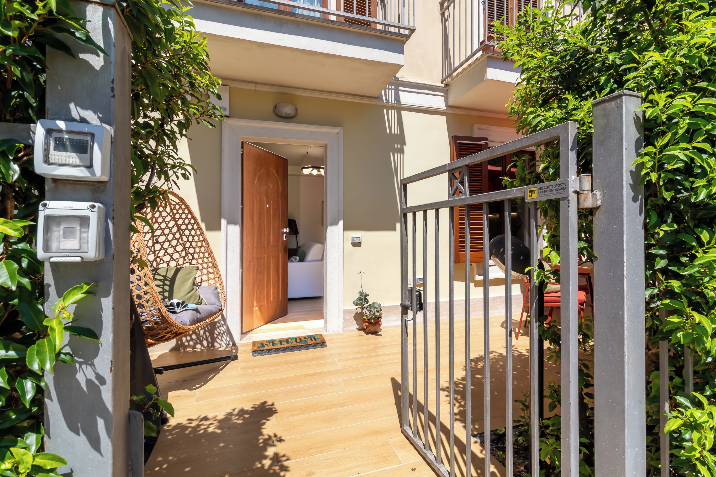 Uma entrada fechada por portão para uma propriedade, com uma porta de madeira, uma cadeira suspensa e um tapete de boas-vindas.
