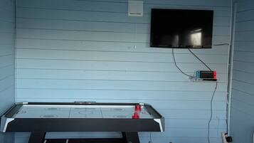A foosball table with a TV mounted on the wall above it.