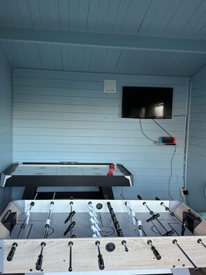 A foosball table with a TV mounted on the wall above it.