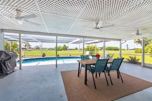 An outdoor covered area with a pool, chairs, and a grill. - Best Deal in Rotonda - Sleeps 8, Pool, Golf, Fun! (Rotonda West)