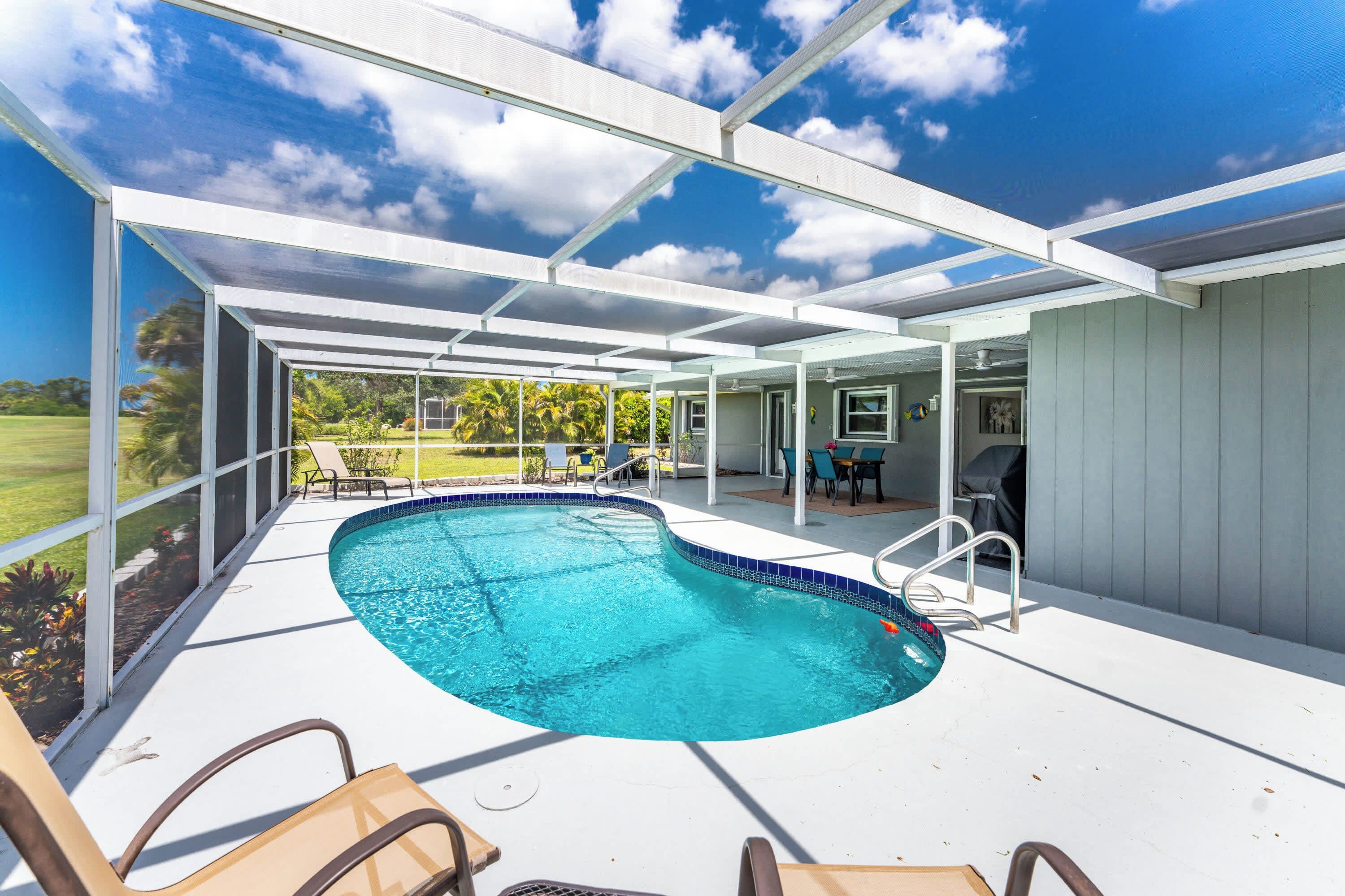 Une piscine couverte avec des chaises longues et vue sur un jardin.