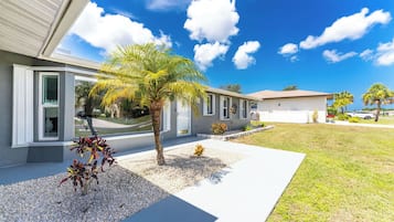 A modern house with a well-maintained lawn, a palm tree, and a driveway leading to the garage.