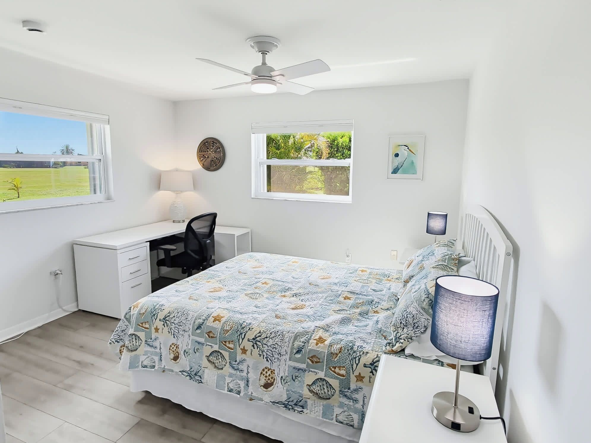 Un dormitorio con cama, escritorio, silla y ventana con vistas a zonas verdes.