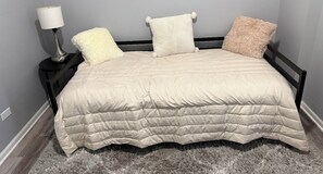 A bed with a quilted cover, two pillows, a bedside lamp, and a fluffy rug. - Spacious 4-bedroom apartment in charming Chicago with AC (Chicago)