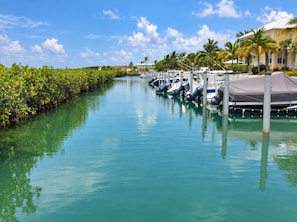 A marina with boats docked, a clear sky, and a waterway lined with vegetation. - Reef House Islamorada | Beach • Pool • Marina (Islamorada)