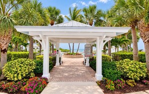 A white gazebo with a brick pathway leading to a circular flower bed, surrounded by palm trees and well-maintained hedges. - Reef House Islamorada | Beach • Pool • Marina (Islamorada)