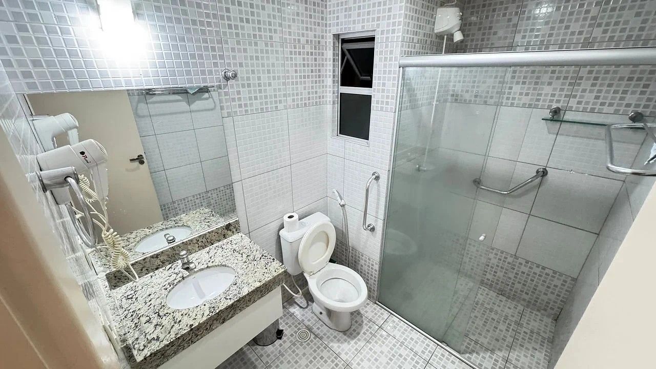 A bathroom with two sinks, a toilet, a shower, and a glass-enclosed shower area.