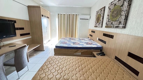 A bedroom with a bed, a desk, a chair, and a television.