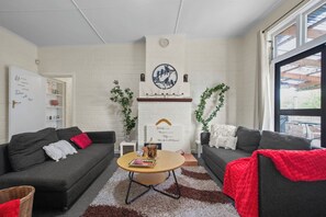 A living room with two sofas, a coffee table, and a white brick wall with a clock and artwork.