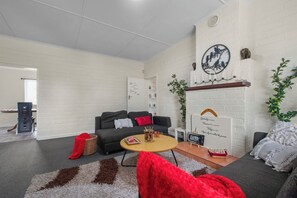 A modern living room with a sofa, a coffee table, and a fireplace. - Cozy Family Home - Manukau City Holiday Home (Manurewa East)