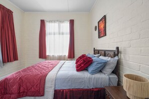 A bedroom with a bed, curtains, a wall clock, and a framed picture. - Cozy Family Home - Manukau City Holiday Home (Manurewa East)