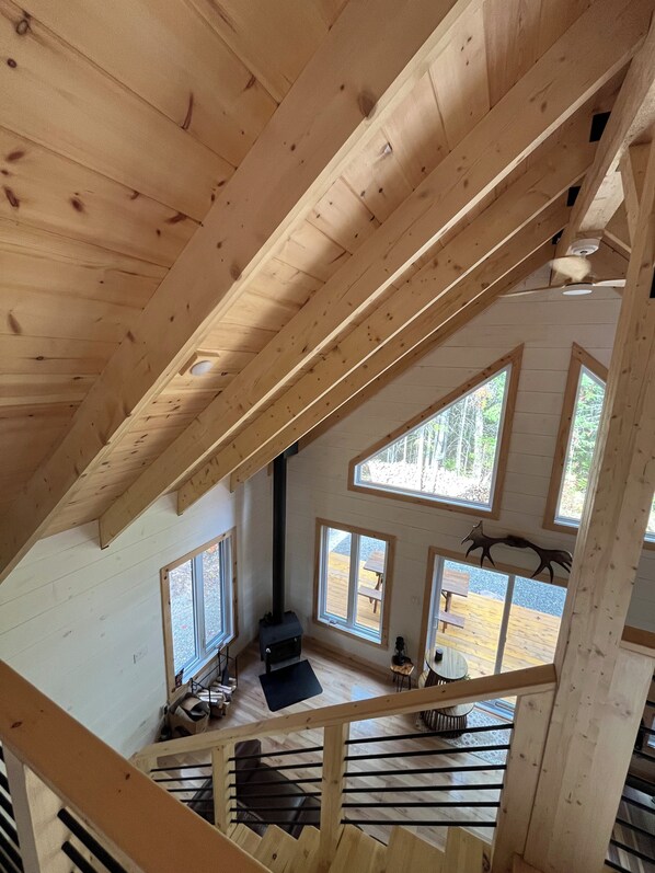 A wooden interior with a high ceiling, multiple windows, and a staircase.