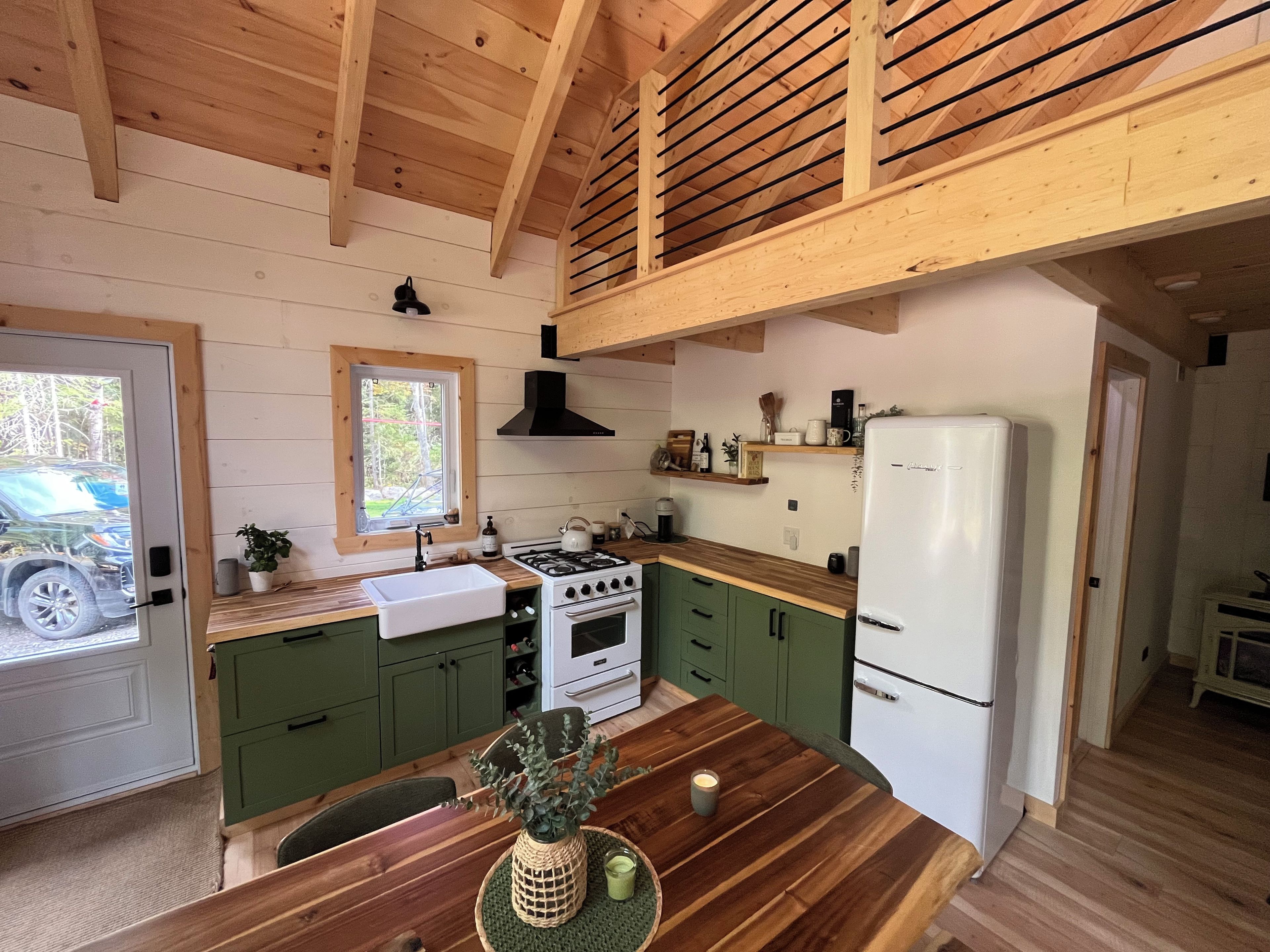 A kitchen with wooden beams, a stove, a sink, and a refrigerator.