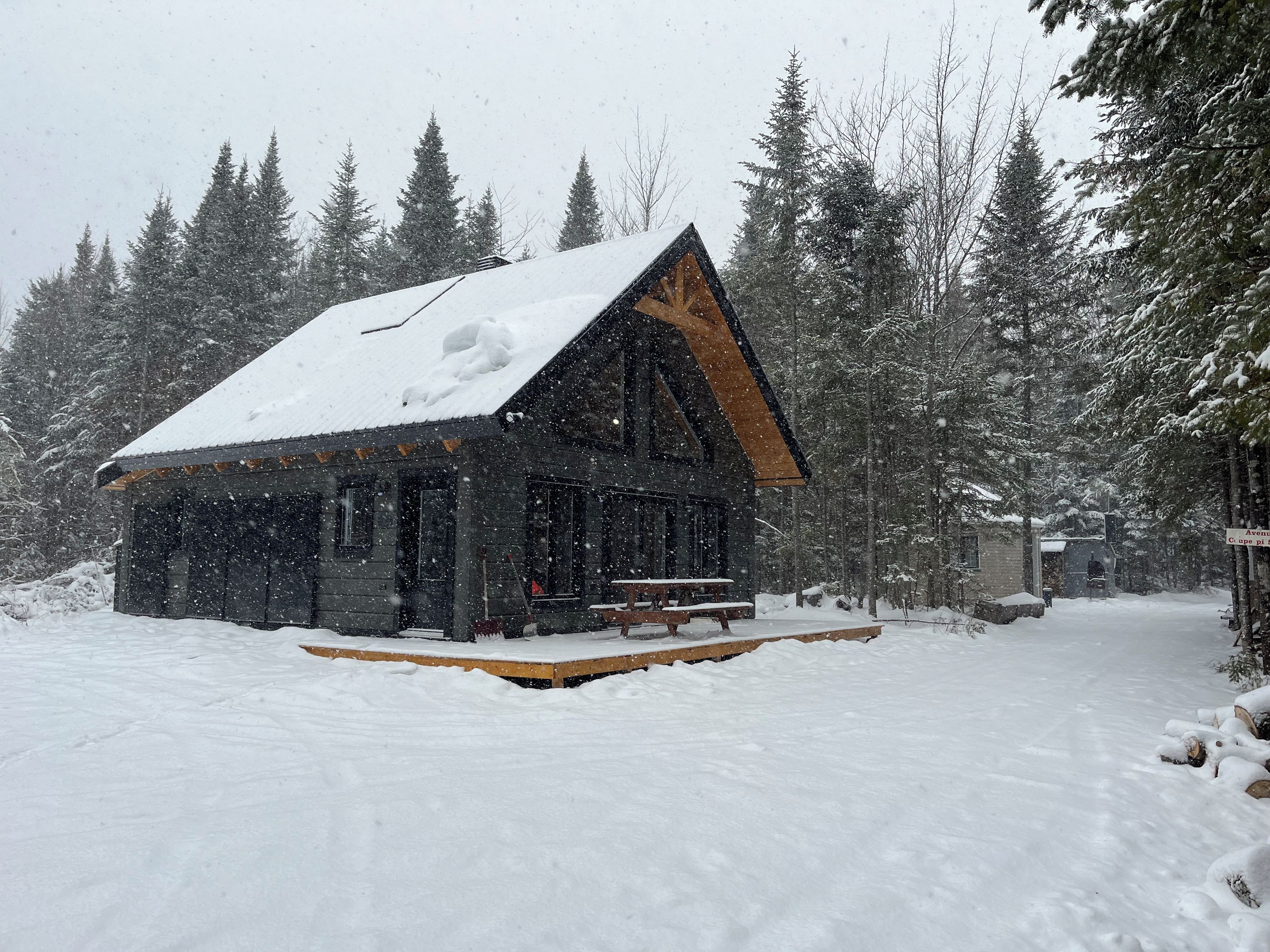 A cabin with a wooden exterior, a porch, and a snow-covered roof.
