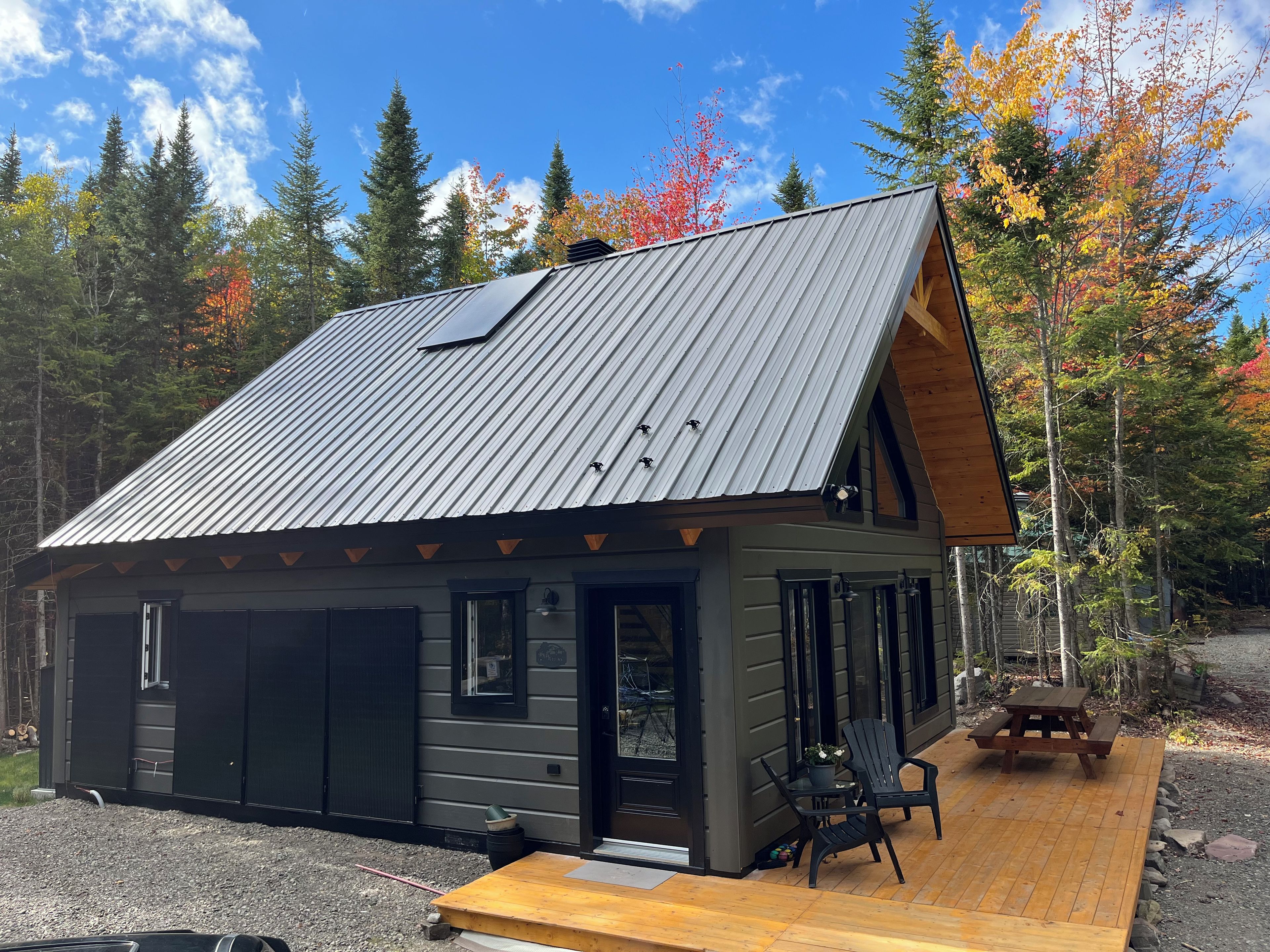 A cabin with a metal roof, a deck, and a small outdoor seating area.