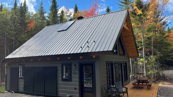 A cabin with a metal roof, a deck, and a small outdoor seating area.