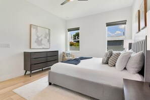 A bedroom with a bed, a dresser, a chair, and a window. - Walk to Raymond James Stadium 3 Bedroom West Tampa Midtown Luxury Home (Tampa)