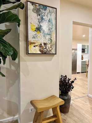 A modern interior with a framed abstract painting, a wooden stool, and a potted plant. - ALEXA Spacious Design Apart up to 10 Pax/Parking (Berlin)