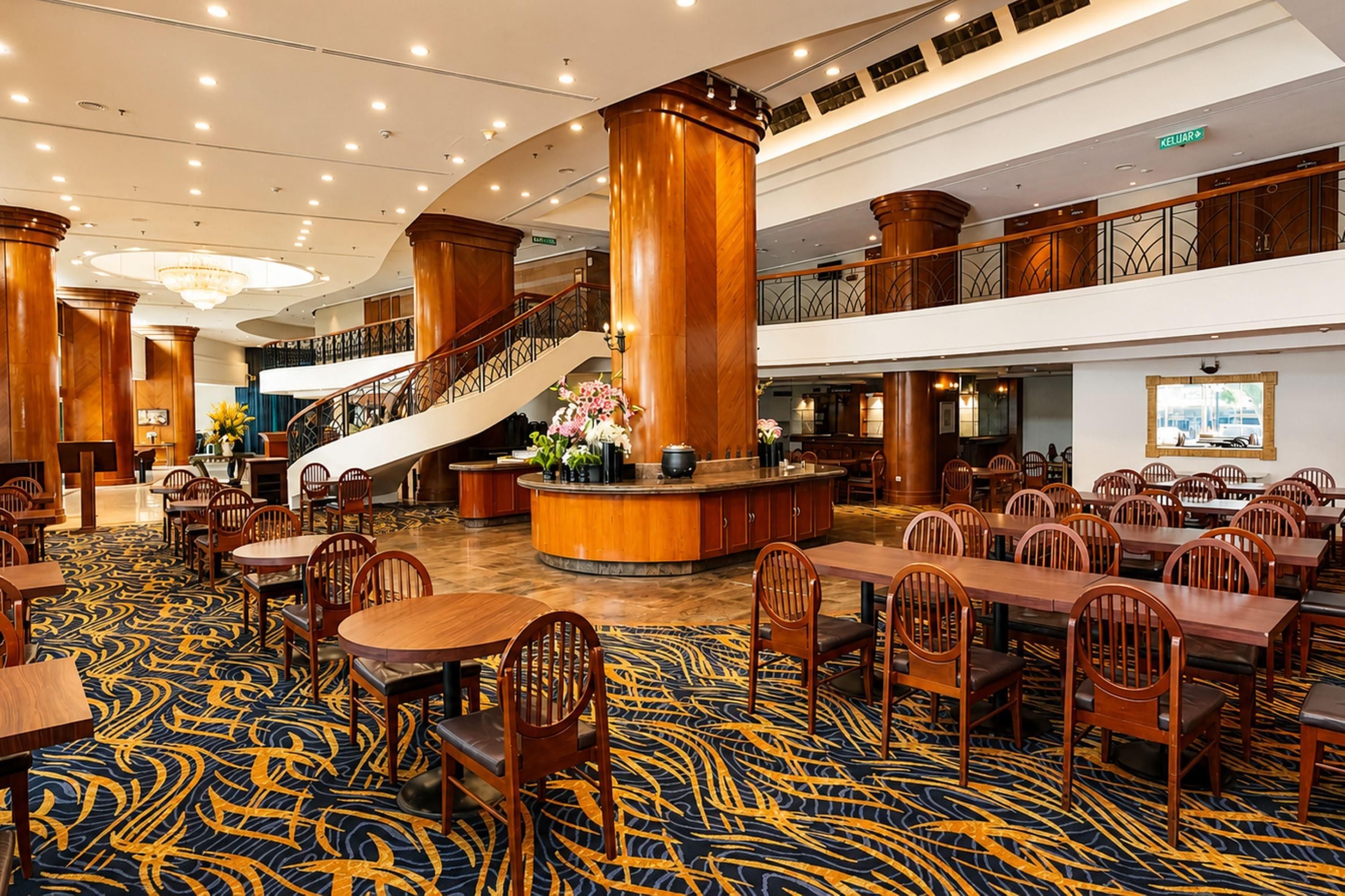 A hotel lobby with a grand staircase, multiple dining areas, and a central reception desk.