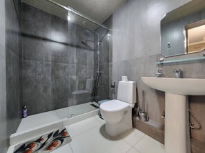 Ein modernes Badezimmer mit Duschkabine aus Glas, Toilette, Waschbecken und Spiegel.