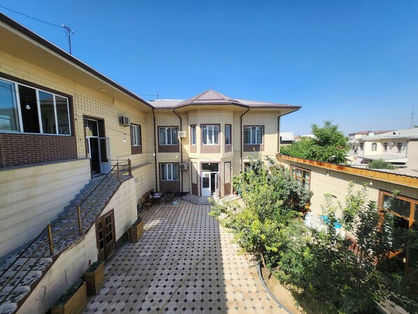 A two-story residential building with a tiled patio, a staircase, and a small garden area. - Room-ideal & Comfort Room for 3 Guests i (Tashkent)