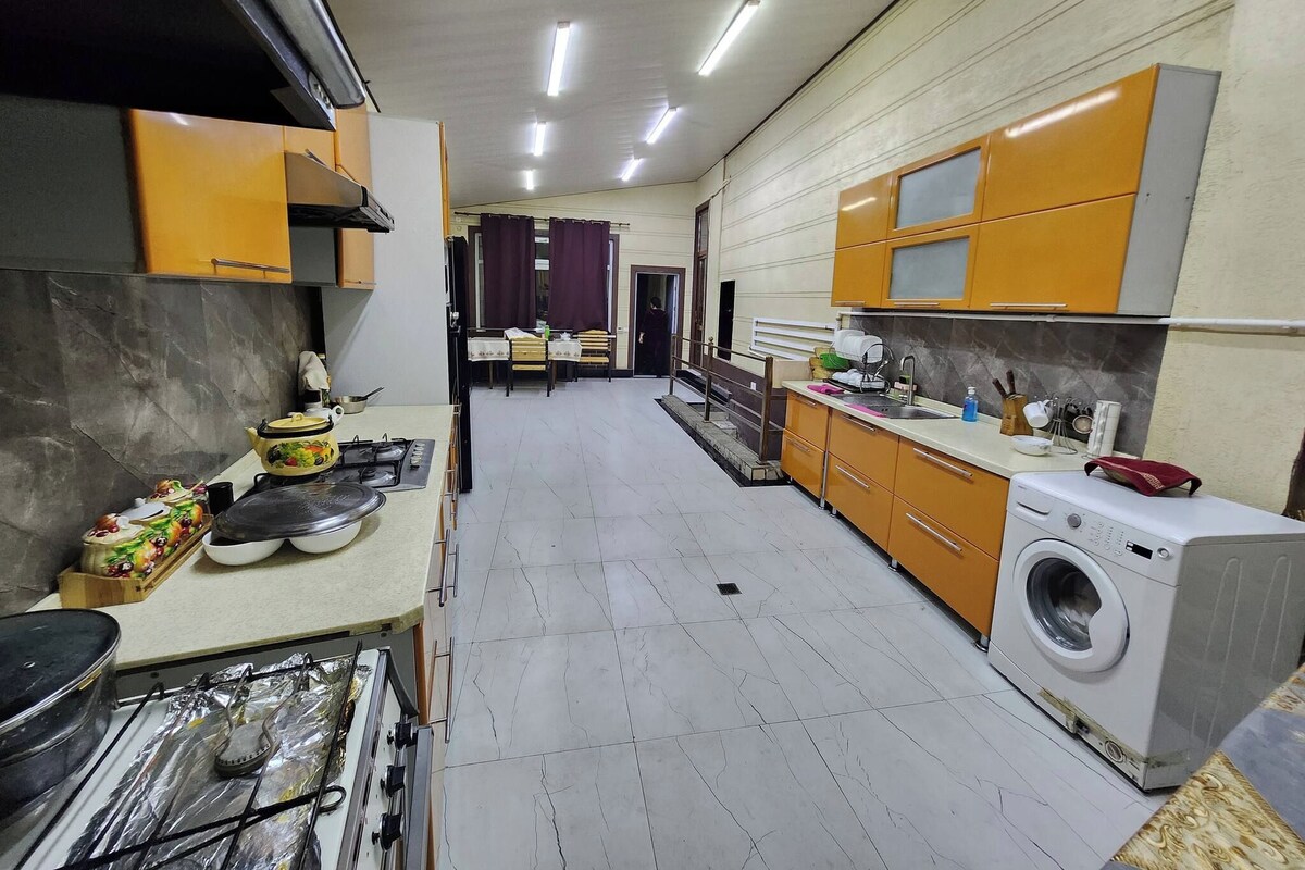 A kitchen with a washing machine, a dining area with a table and chairs, and a view into another room.