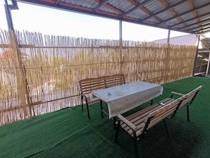 An outdoor seating area with a table and benches, surrounded by a bamboo fence. - Room-ideal & Comfort Room for 3 Guests i (Tashkent)
