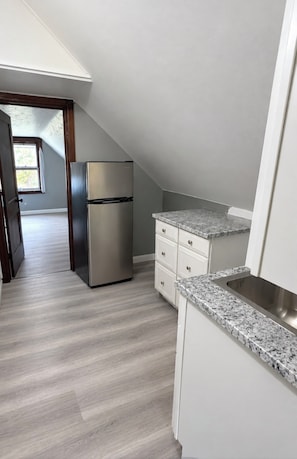 Une cuisine dotée d’un réfrigérateur en acier inoxydable, de meubles blancs et d’un plan de travail en granit.