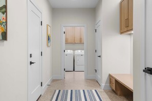 A narrow hallway with a bench, a washing machine, and a dryer. - Firefly Landing | Pet Friendly | Golf (Elk Rapids)