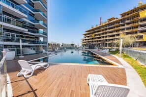 Ett modernt hotell med en pool på taket, glasräcken och utsikt över stadens silhuett.