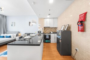 Uma cozinha moderna com uma ilha central, uma sala de jantar com um sofá e uma sala de estar com uma cama.