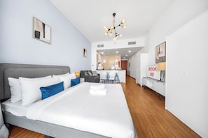 A modern hotel room with a large bed, a kitchenette, a dining area, and a TV. - StayShort - Studio with best skyline view in JVT for 2! (JVT)