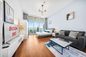 Quarto de hotel moderno com uma cama grande, um sofá, uma escrivaninha e vista para a cidade.