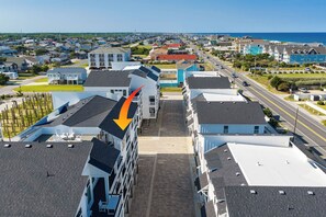 A residential area with multiple-story buildings, a clear sky, and a view of the ocean. - Brand New Condo w/ Ocean Views, Elevator, Pool! (Kill Devil Hills)