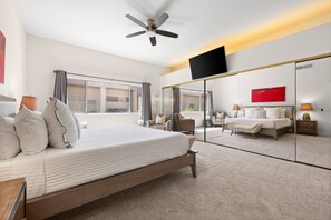 A hotel room with a bed, a ceiling fan, a large mirror, a TV, and a view of the outside. - Private Pool & Firepit Escape in Mission Hills Country Club | Mountain Views, Golf & Pickleball (Rancho Mirage)